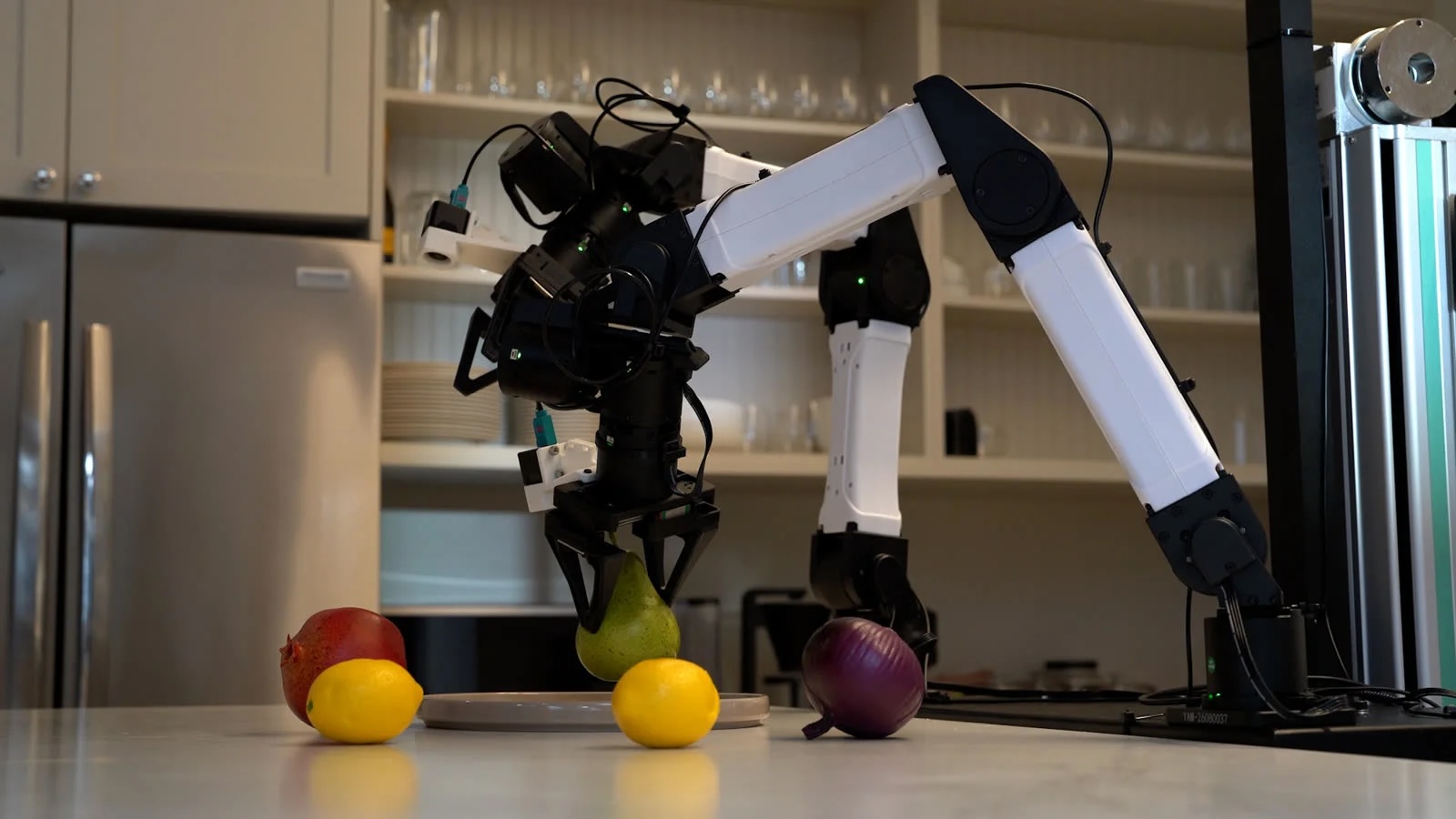 Two robot arms from Runway AI picking up fruit in a kitchen.