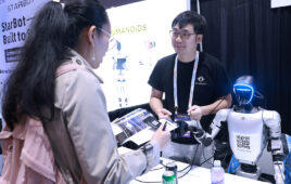 A woman talking to a man and a humanoid robot at RoboBusiness 2025.